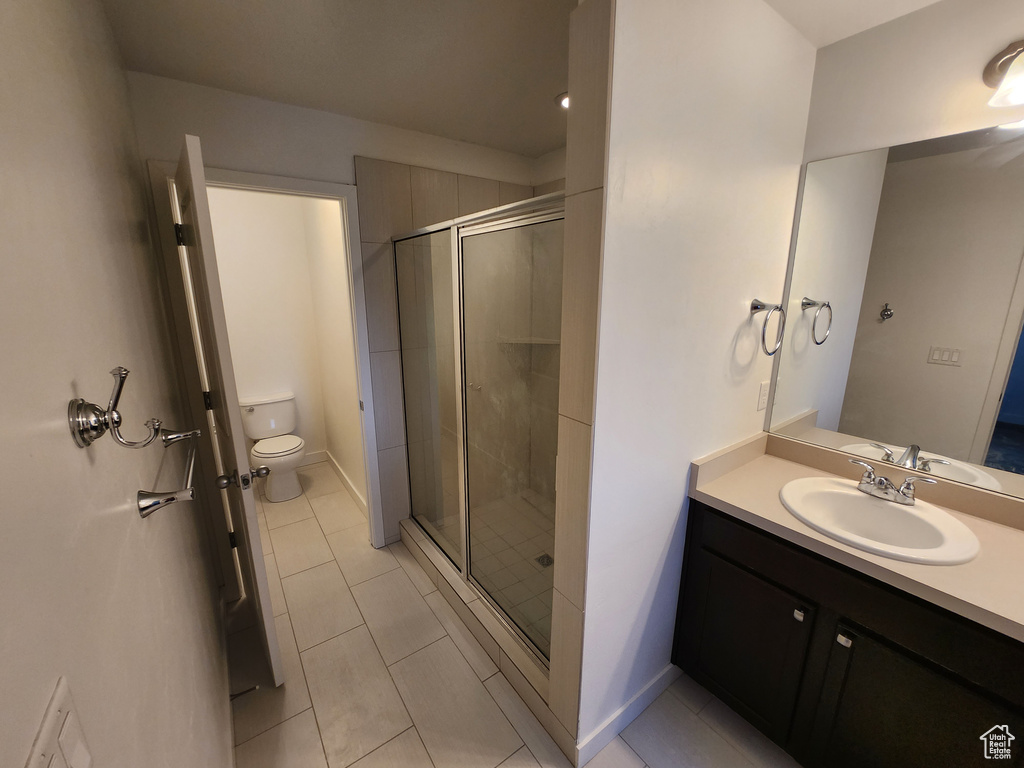 Full bath featuring toilet, a stall shower, vanity, tile patterned flooring, and baseboards