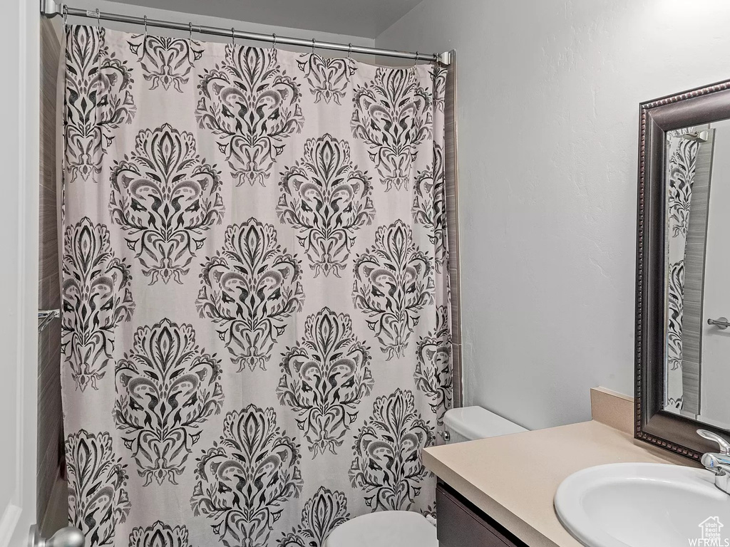 Bathroom featuring toilet, vanity, and a shower with shower curtain