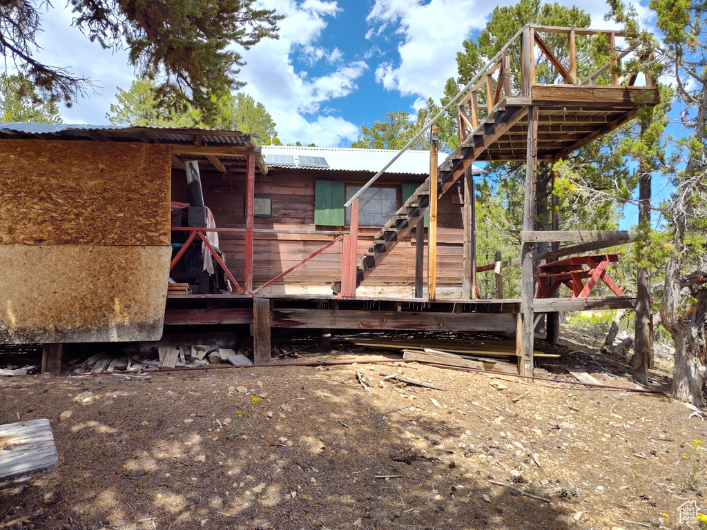 Rear view of house featuring stairway and metal roof