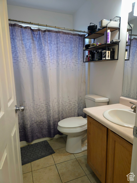 Bathroom featuring tile patterned flooring, vanity, toilet, and a shower with curtain