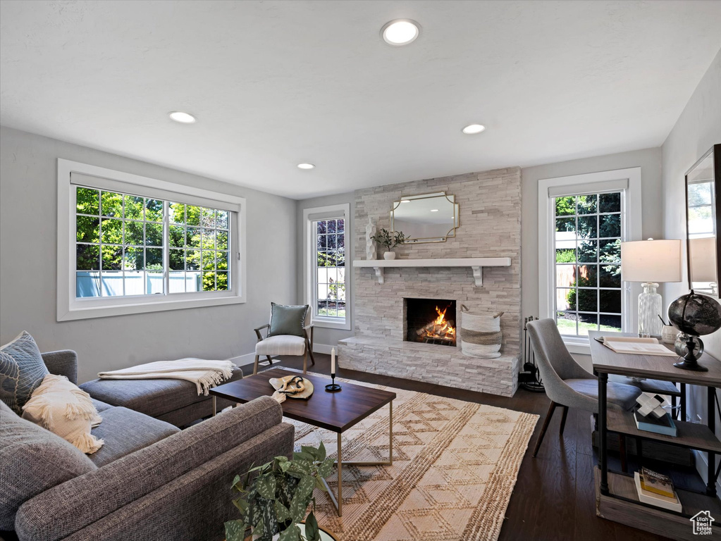 Living room with a fireplace, dark wood-style flooring, and recessed lighting