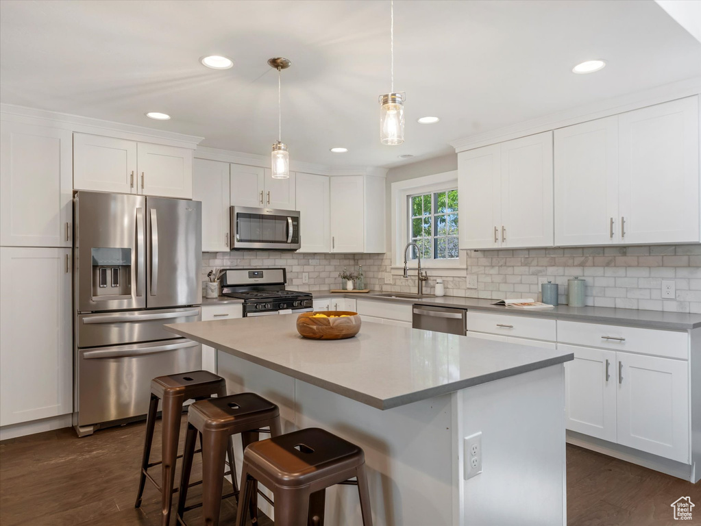 Kitchen featuring stainless steel appliances, a sink, white cabinetry, a kitchen breakfast bar, and recessed lighting
