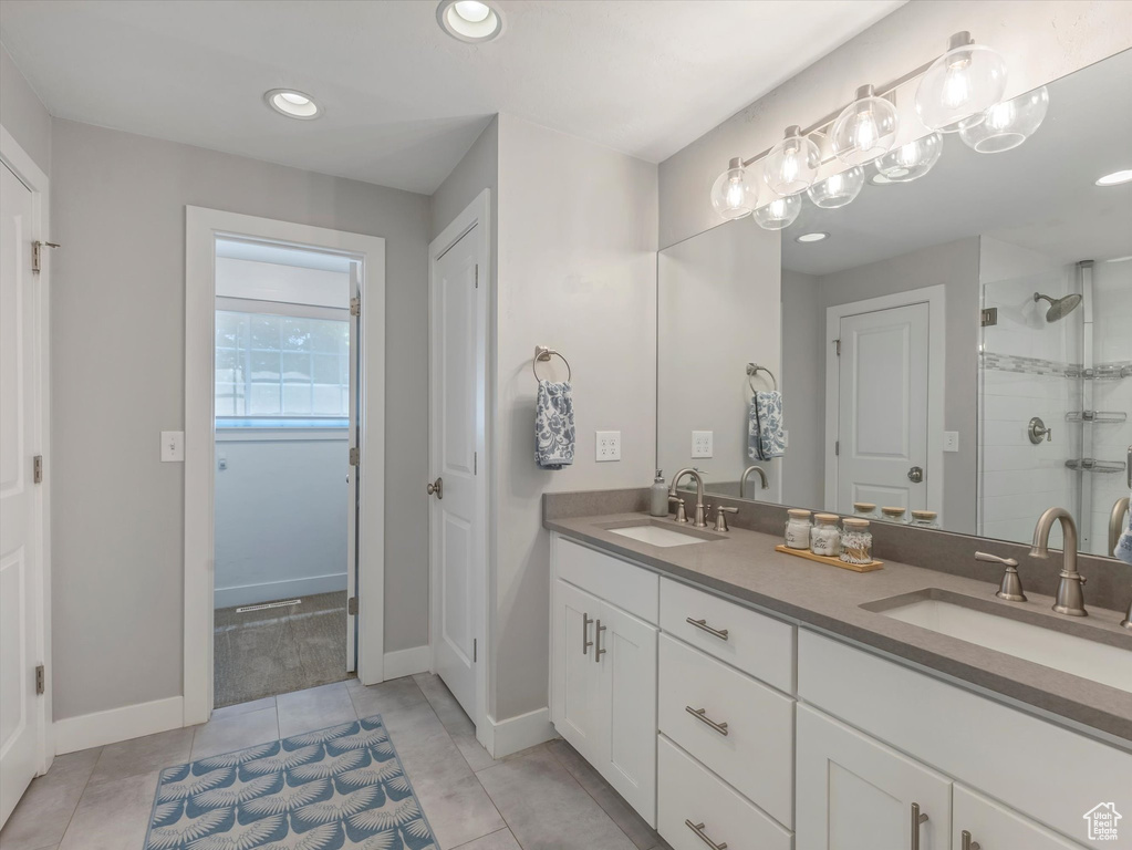 Full bath with a stall shower, double vanity, tile patterned floors, baseboards, and recessed lighting