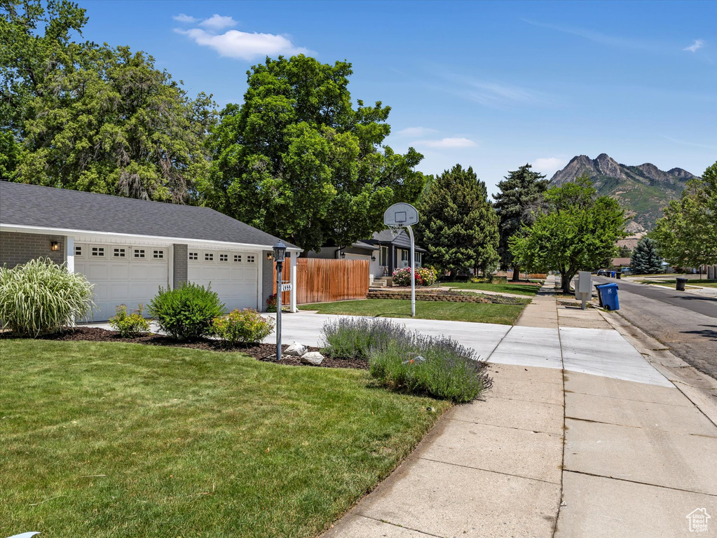 View of yard with concrete driveway, a mountain view, and an attached garage
