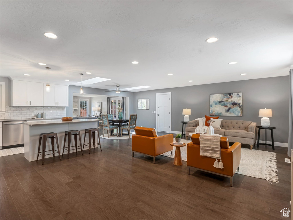 Living area with dark wood-type flooring, recessed lighting, a skylight, and baseboards