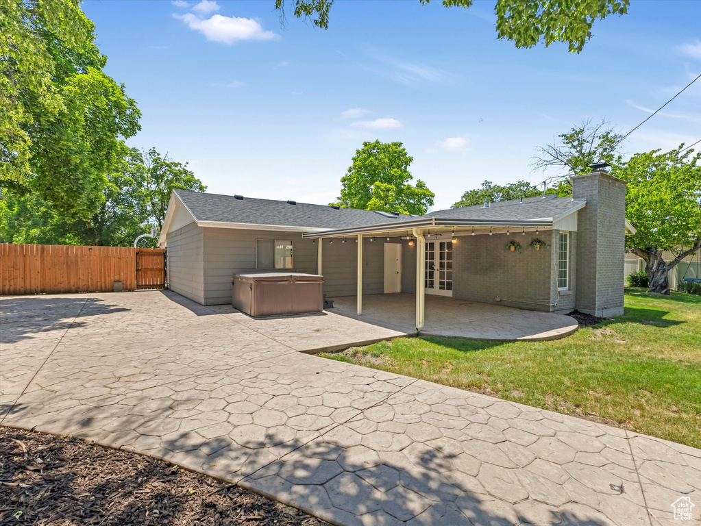 Rear view of property featuring a hot tub, a patio, french doors, a chimney, and roof with shingles