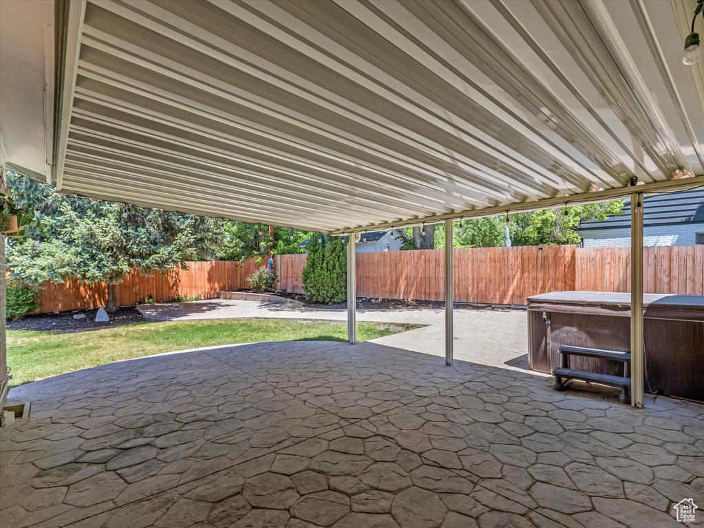 Fenced backyard featuring a hot tub and a patio