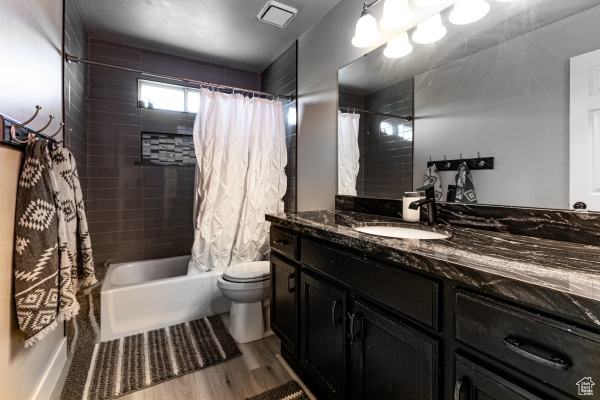 Full bathroom with vanity, shower / bath combination with curtain, toilet, and wood finished floors