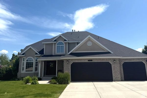 View of front facade with driveway, brick siding, a front yard, and an attached garage