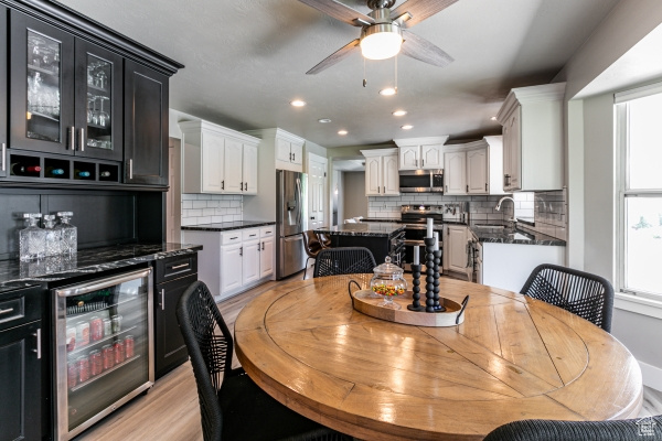 Dining space with beverage cooler, a ceiling fan, healthy amount of natural light, recessed lighting, and light wood-style floors