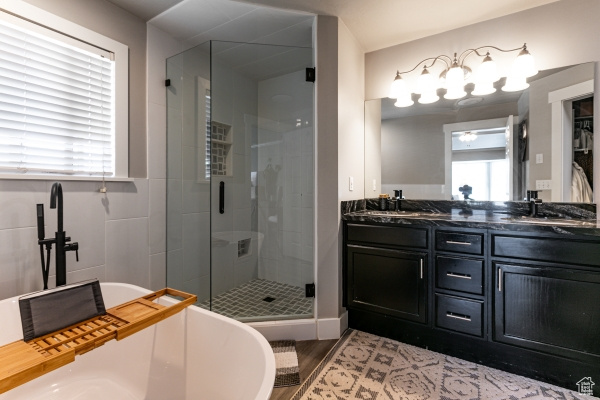 Bathroom with a stall shower, double vanity, a freestanding tub, and wood finished floors