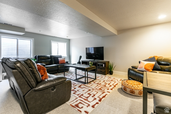 Living room featuring light carpet, a textured ceiling, and baseboards