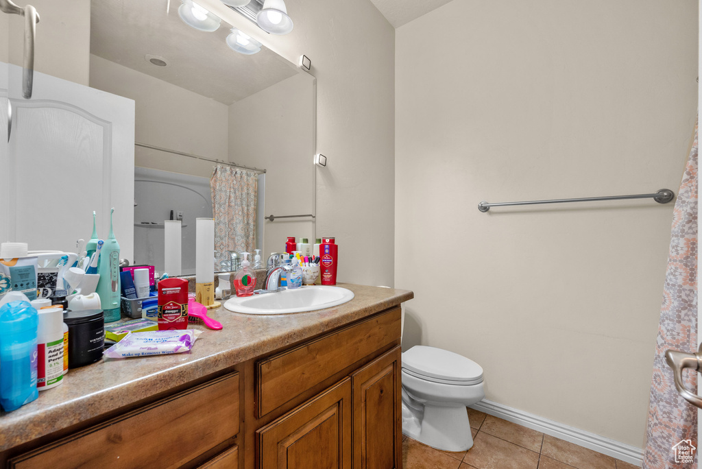 Bathroom with tile patterned floors, vanity, toilet, and a shower with shower curtain