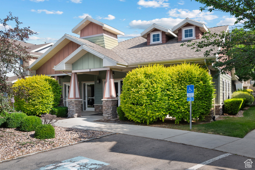Craftsman-style home with board and batten siding, roof with shingles, and stone siding