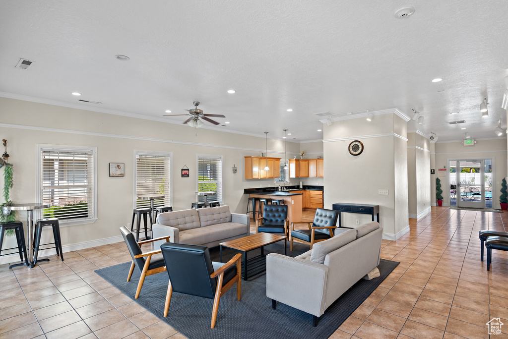 Living area with light tile patterned floors, a ceiling fan, ornamental molding, recessed lighting, and baseboards
