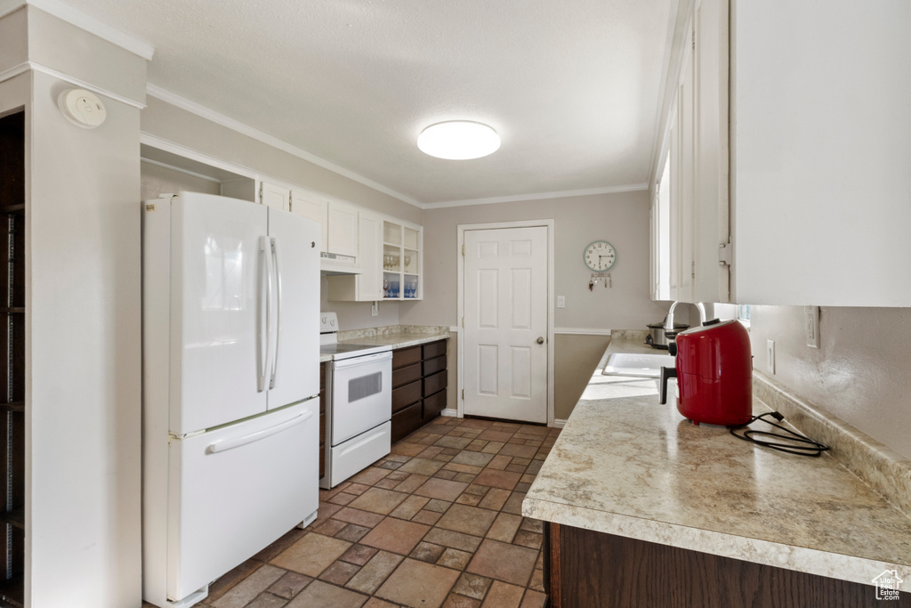 Kitchen featuring white appliances, a sink, light countertops, white cabinetry, and light stone finish flooring