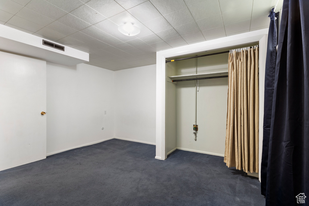Unfurnished bedroom with dark carpet, a closet, and baseboards