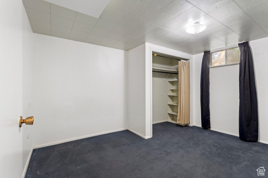 Unfurnished bedroom featuring dark carpet, baseboards, and a closet