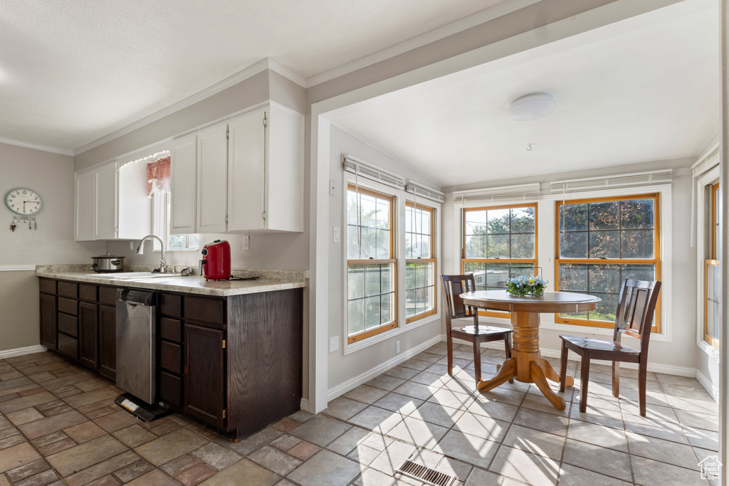 Kitchen with baseboards, a sink, light countertops, dishwasher, and white cabinets