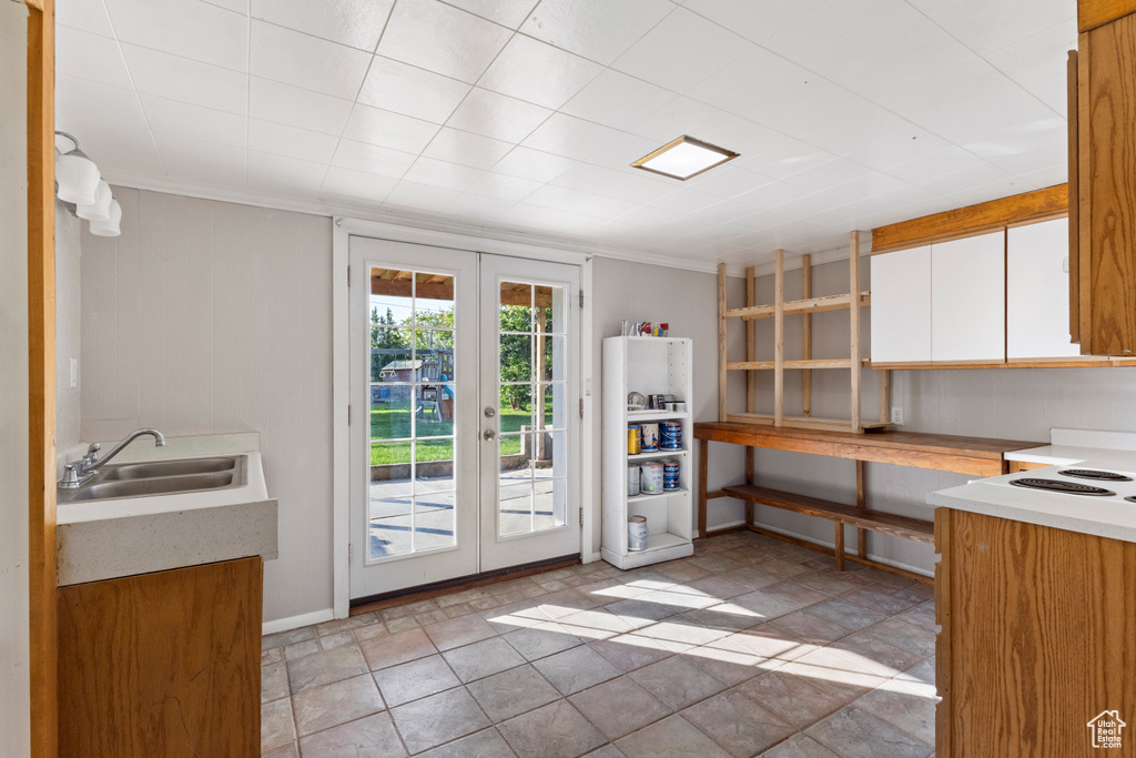 Kitchen featuring french doors, a sink, white cabinetry, light countertops, and crown molding