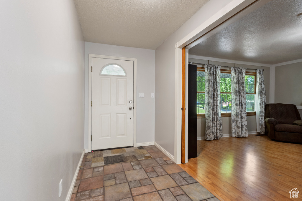 Foyer featuring a textured ceiling, baseboards, and stone finish flooring
