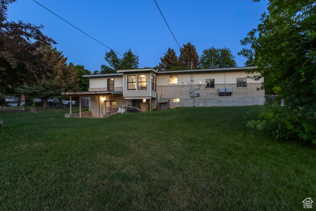 Rear view of house with a lawn and brick siding
