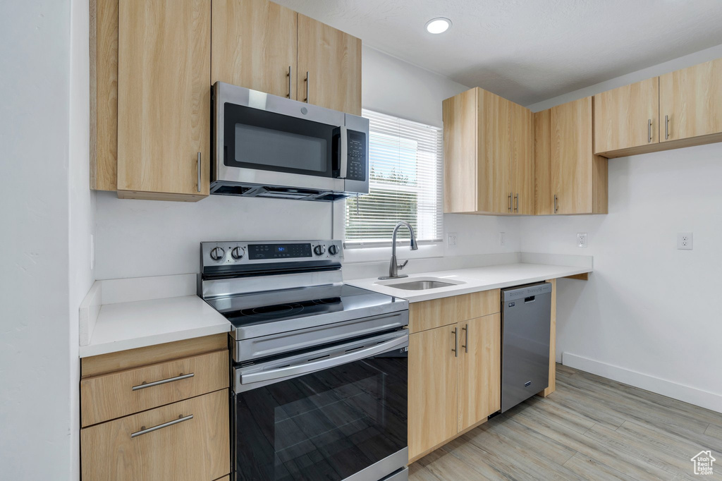 Kitchen featuring stainless steel appliances, light brown cabinetry, a sink, light countertops, and recessed lighting
