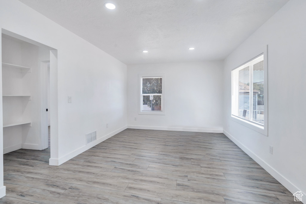 Unfurnished bedroom featuring recessed lighting, wood finished floors, a spacious closet, baseboards, and a closet