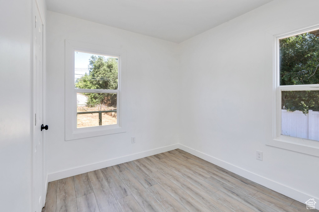 Spare room featuring healthy amount of natural light, light wood-style flooring, and baseboards