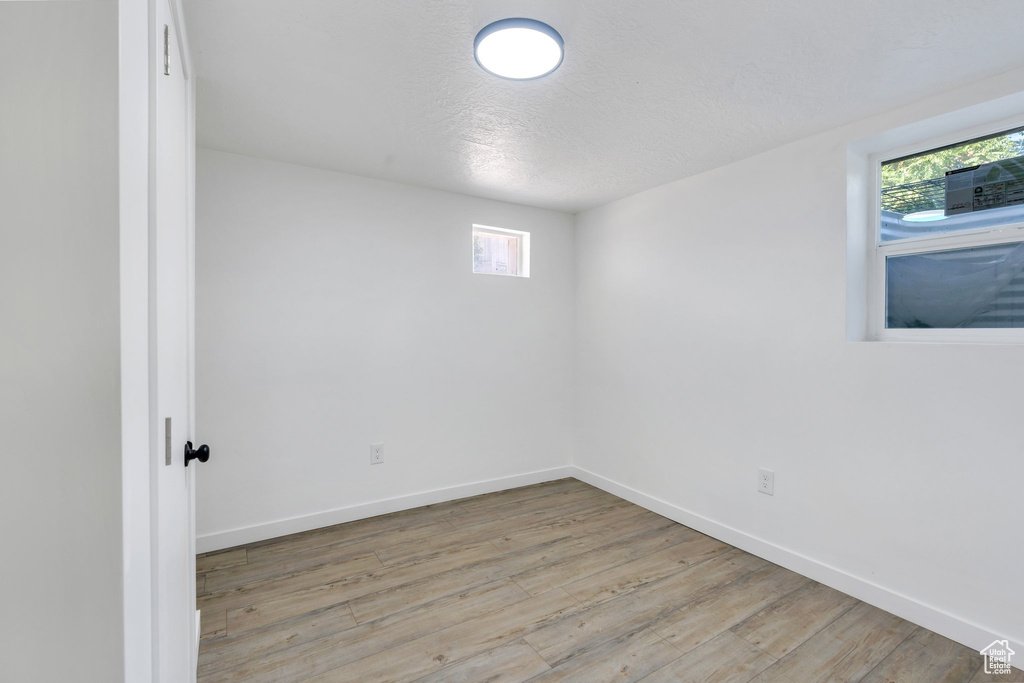 Unfurnished room featuring plenty of natural light, wood finished floors, baseboards, and a textured ceiling