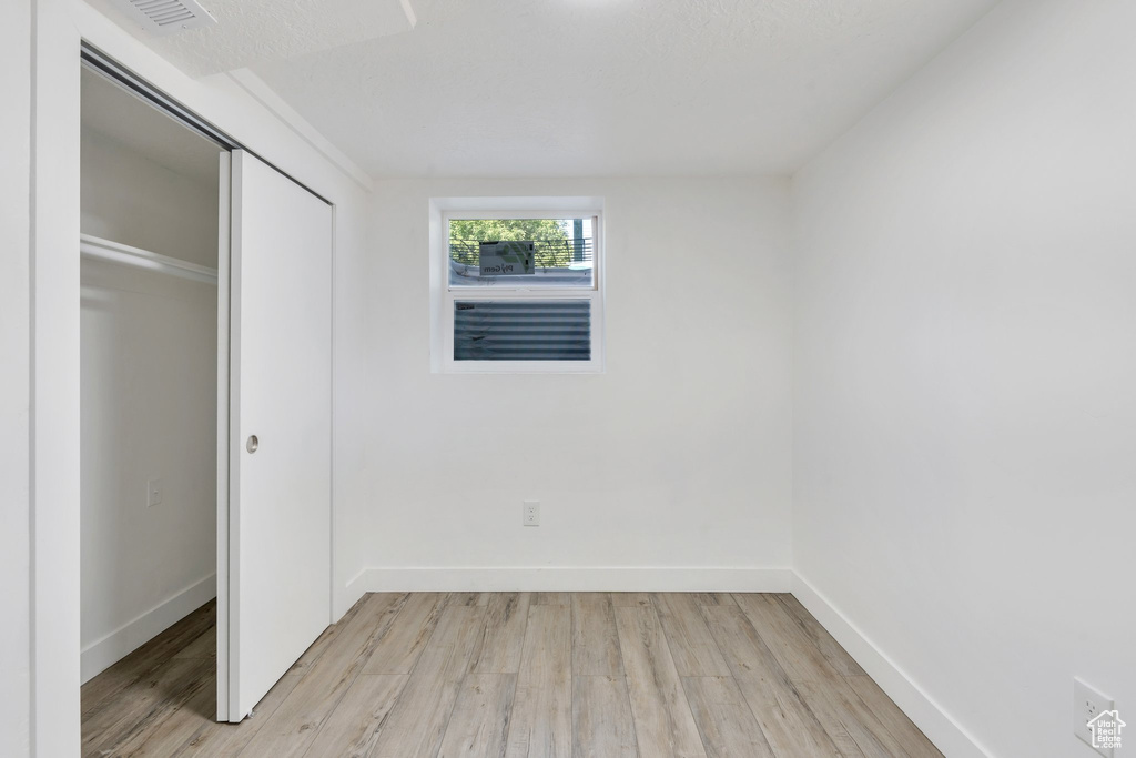 Unfurnished bedroom with light wood-type flooring, a closet, and baseboards