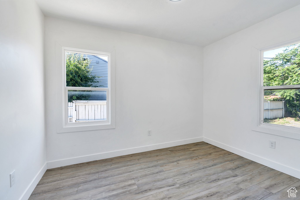 Unfurnished room featuring plenty of natural light, light wood-style flooring, and baseboards
