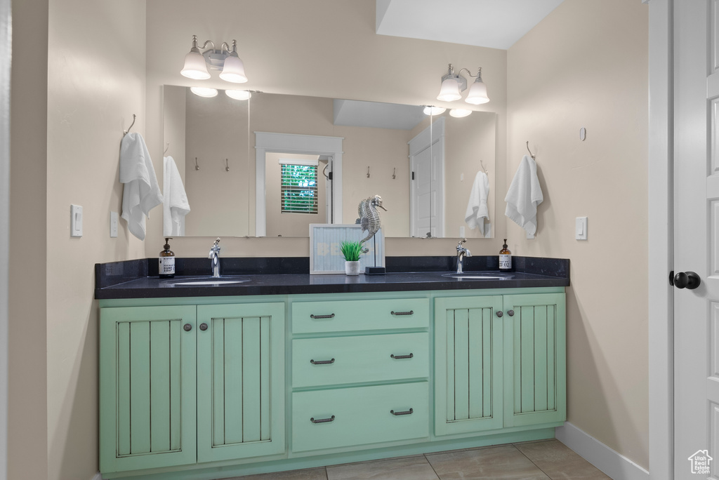 Bathroom featuring double vanity, baseboards, and tile patterned floors