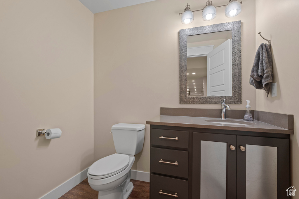 Bathroom featuring toilet, wood finished floors, vanity, and baseboards