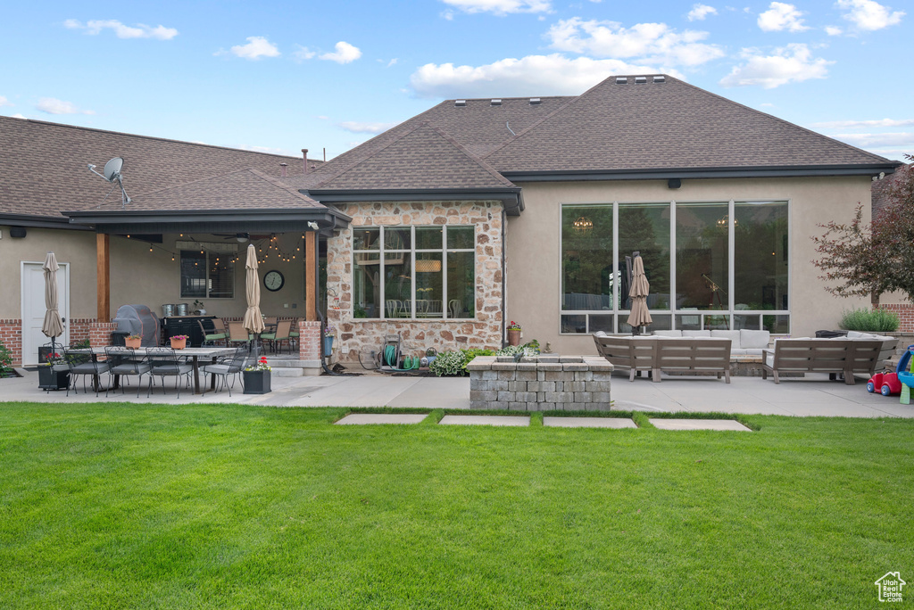 Rear view of property with an outdoor living space, a patio, roof with shingles, stucco siding, and a lawn