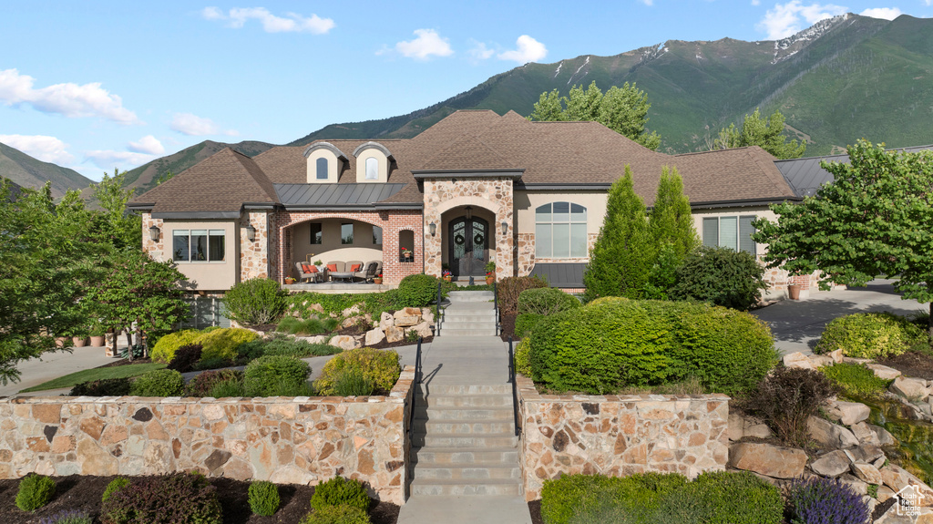 French country inspired facade featuring a mountain view, brick siding, and a standing seam roof