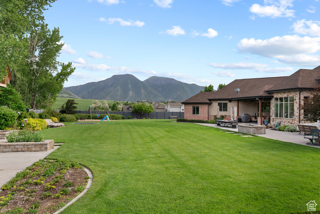 View of yard with a playground, a patio area, a mountain view, and a fire pit