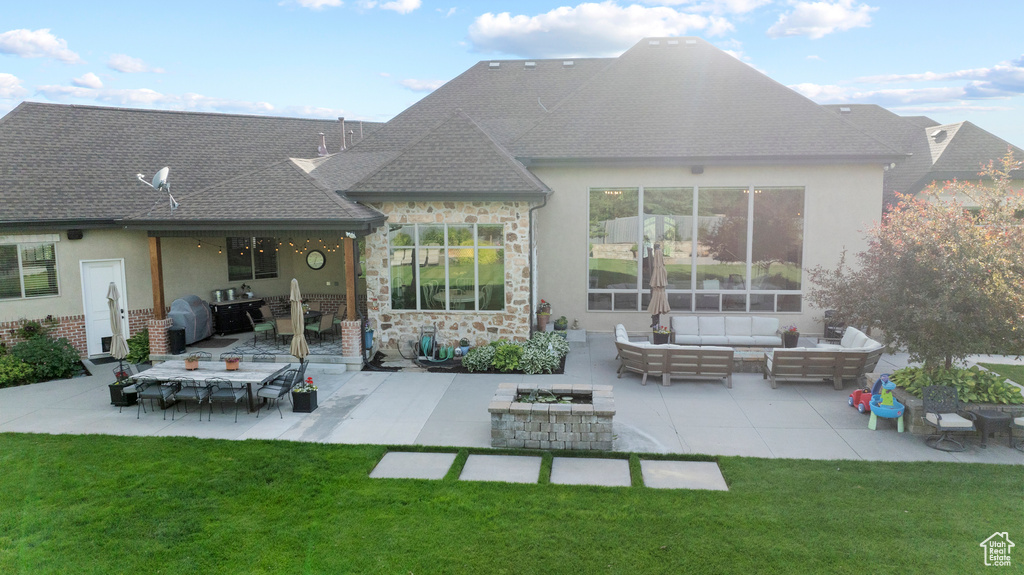 Back of property featuring an outdoor living space with a fire pit, a patio, a lawn, and stucco siding