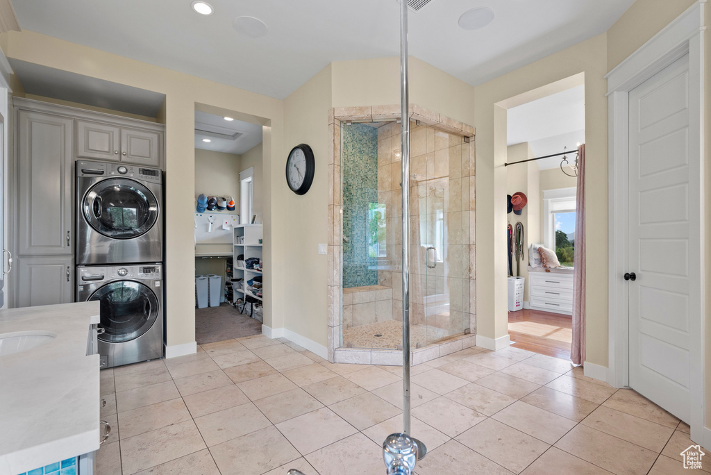 Full bathroom featuring stacked washer / drying machine, a stall shower, tile patterned flooring, baseboards, and recessed lighting