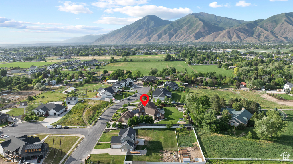 Aerial view of property and surrounding area featuring mountains and nearby suburban area