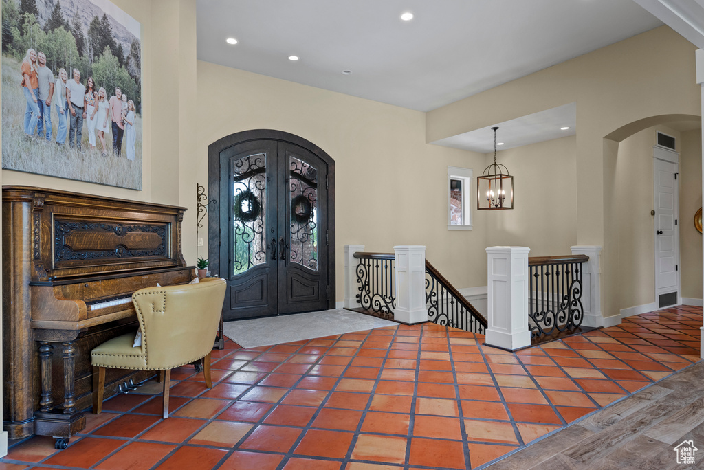 Entryway featuring arched walkways, french doors, recessed lighting, tile patterned floors, and a chandelier