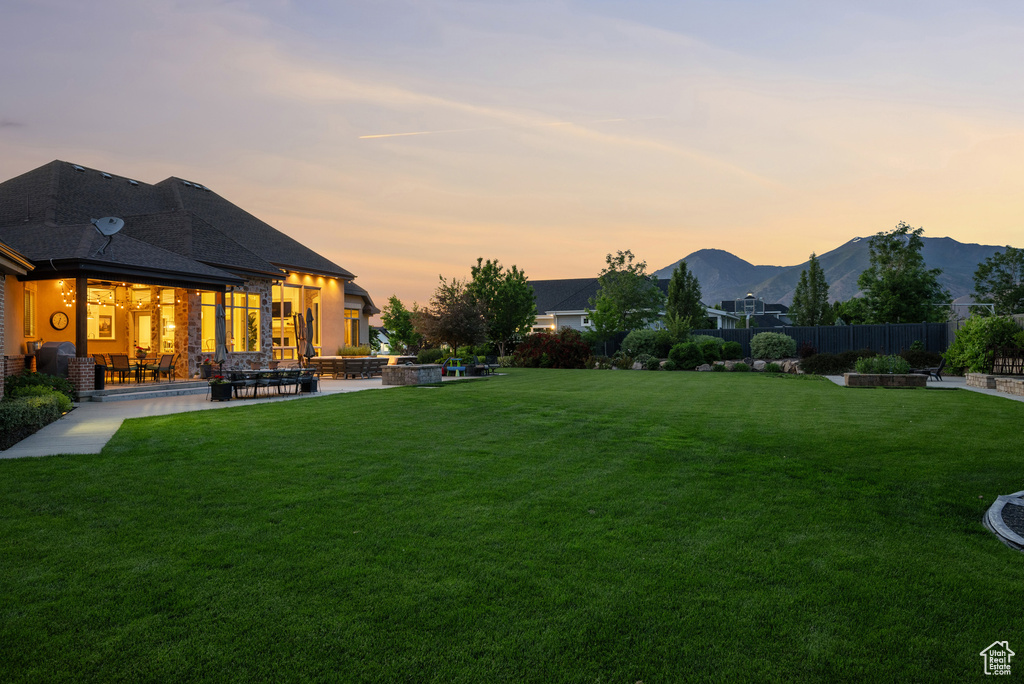Yard at dusk featuring a mountain view and a patio area