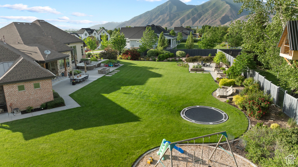 View of yard with a patio, a residential view, a trampoline, and a mountain view