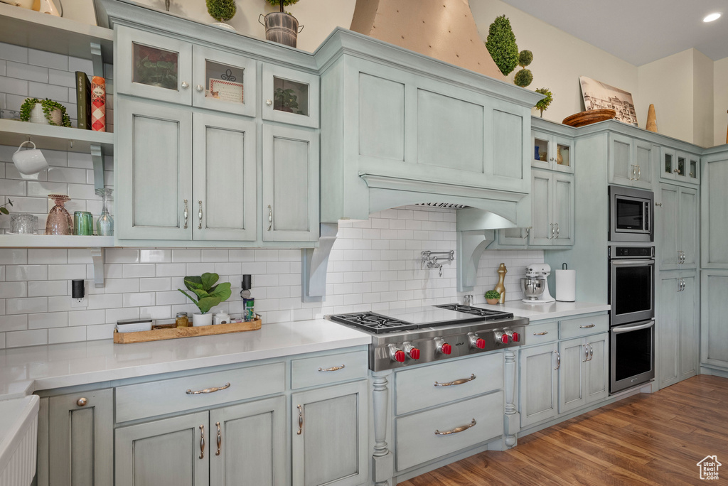 Kitchen featuring open shelves, appliances with stainless steel finishes, light countertops, and backsplash