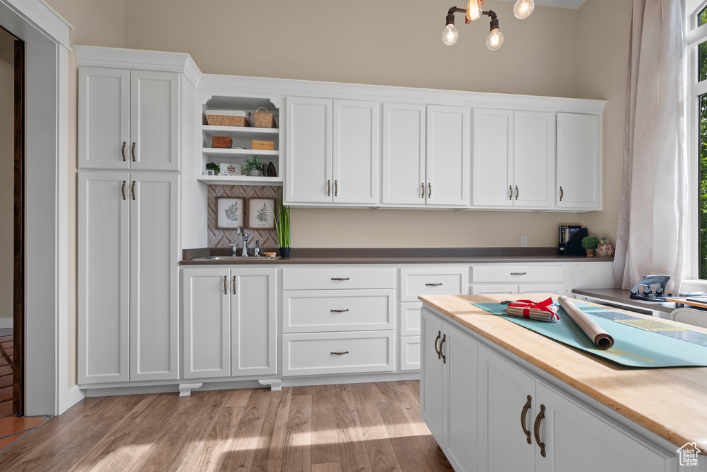 Kitchen featuring open shelves, a sink, white cabinetry, and light wood-style floors