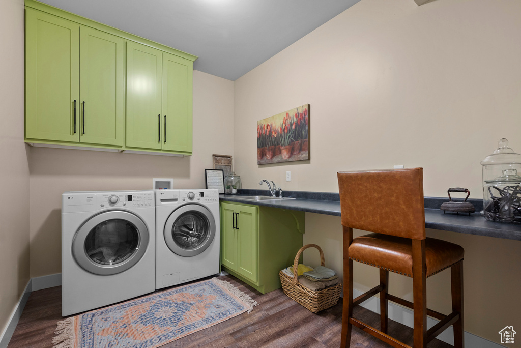 Laundry area featuring washing machine and dryer, cabinet space, dark wood-style flooring, and baseboards