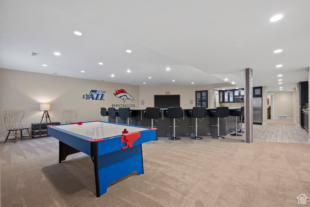 Game room with light colored carpet, wet bar, and recessed lighting