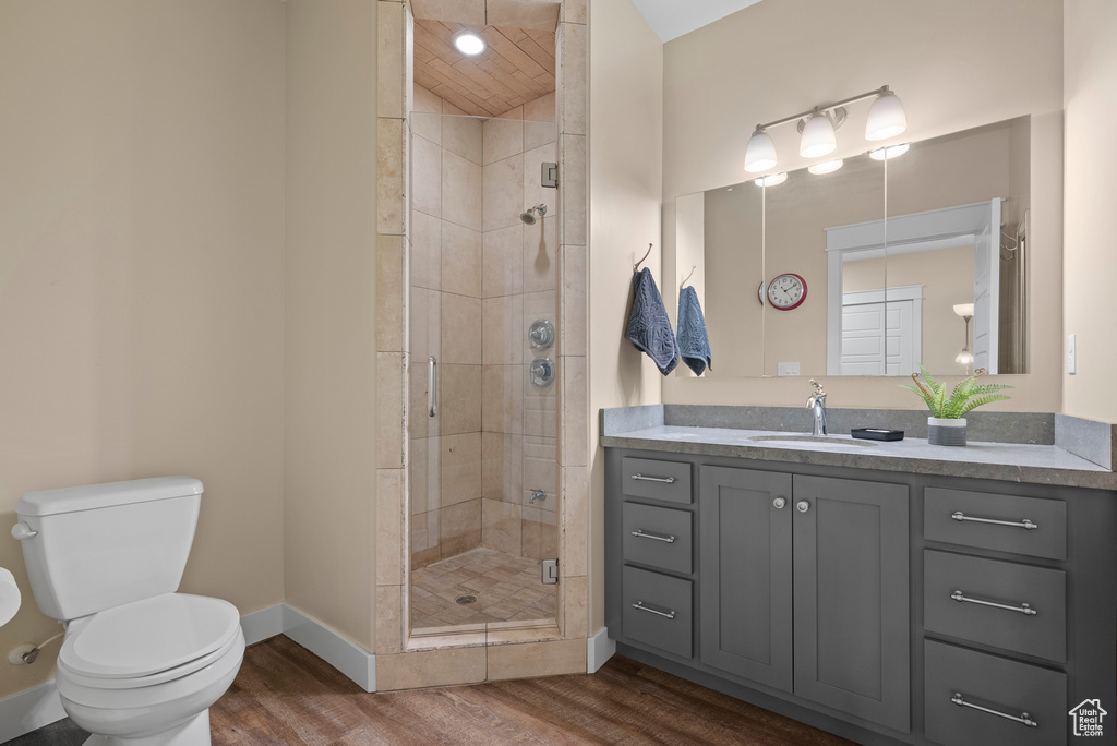 Bathroom with vanity, toilet, wood finished floors, a stall shower, and baseboards