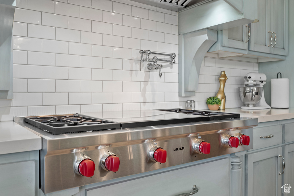 Kitchen with stainless steel gas cooktop, decorative backsplash, and light countertops