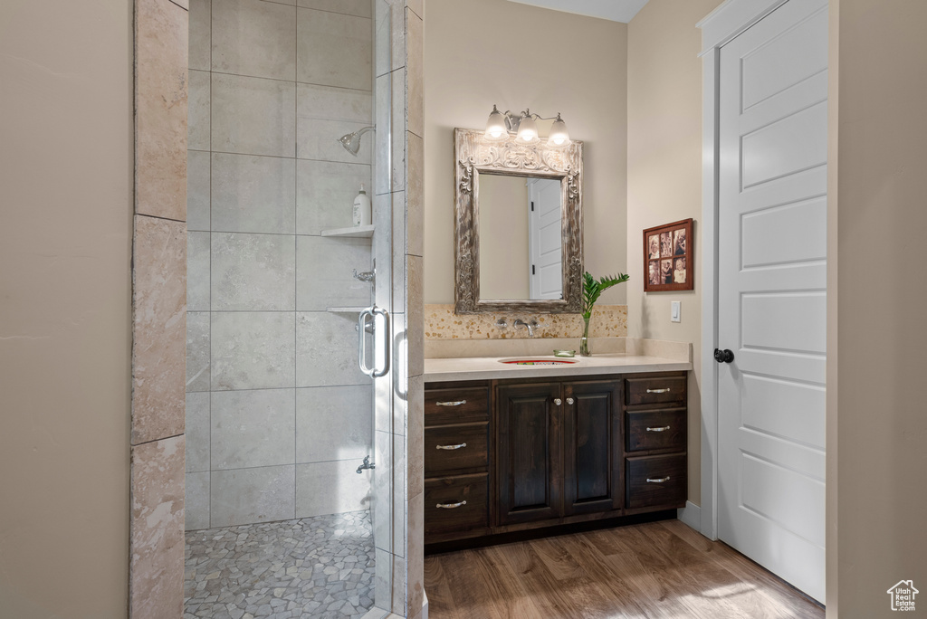 Full bath with a stall shower, vanity, and wood finished floors